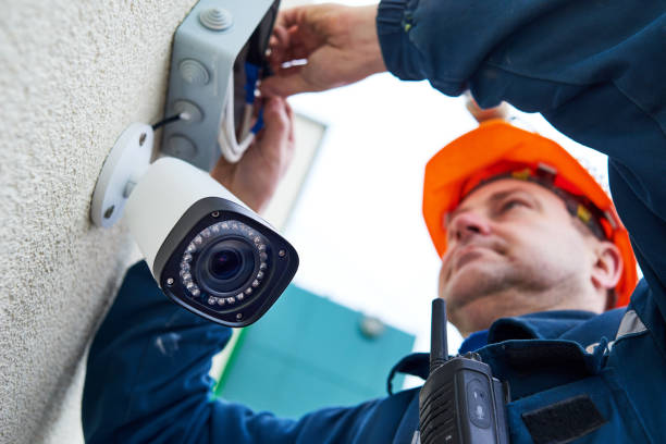 Video surveillance. Technician worker installing wall camera with screwdriver